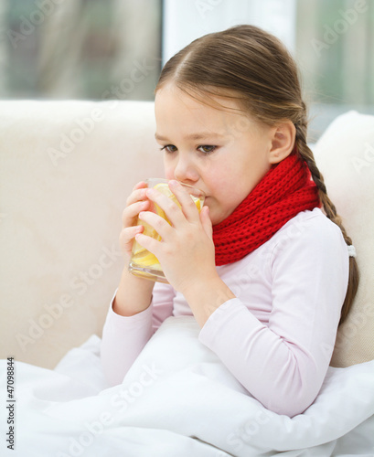 Ill little girl is drinking vitamin cocktail