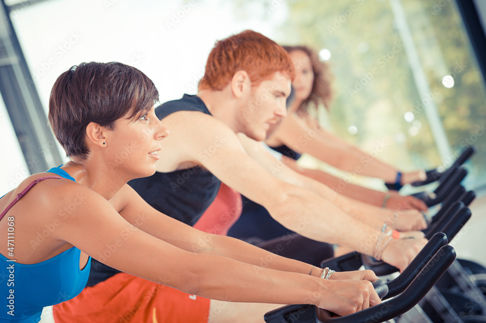 Group of five people in the gym, exercising their legs doing car Group of five people in the gym, exercising their legs doing car