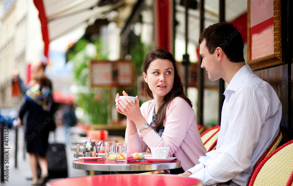 Happy couple drinking coffee or tea in a Parisian outdoor cafe