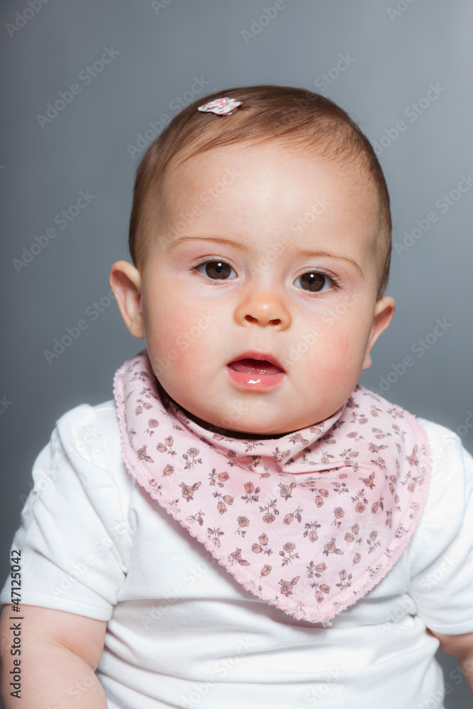 Cute baby girl against grey background. Studio shot.