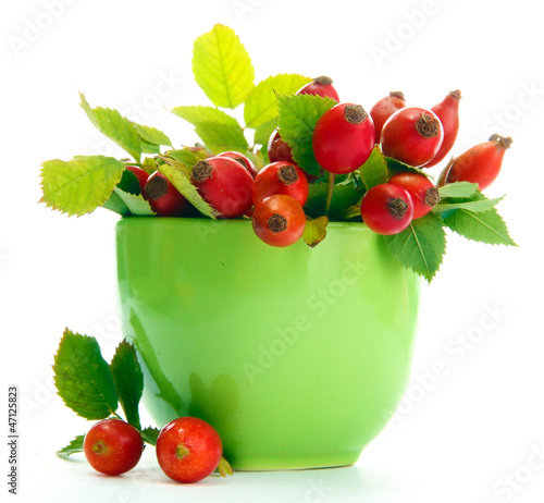 ripe hip roses with leaves in cup, isolated on white photo