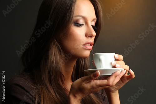 beautiful young woman with cup of coffee, on brown background