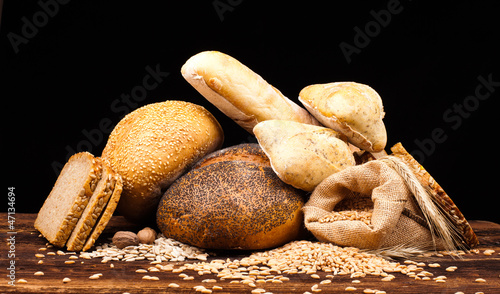 assortment of baked bread on wooden table and black background
