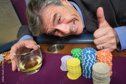 Cuadro en lienzo Man leaning on table with whiskey glass giving thumbs up