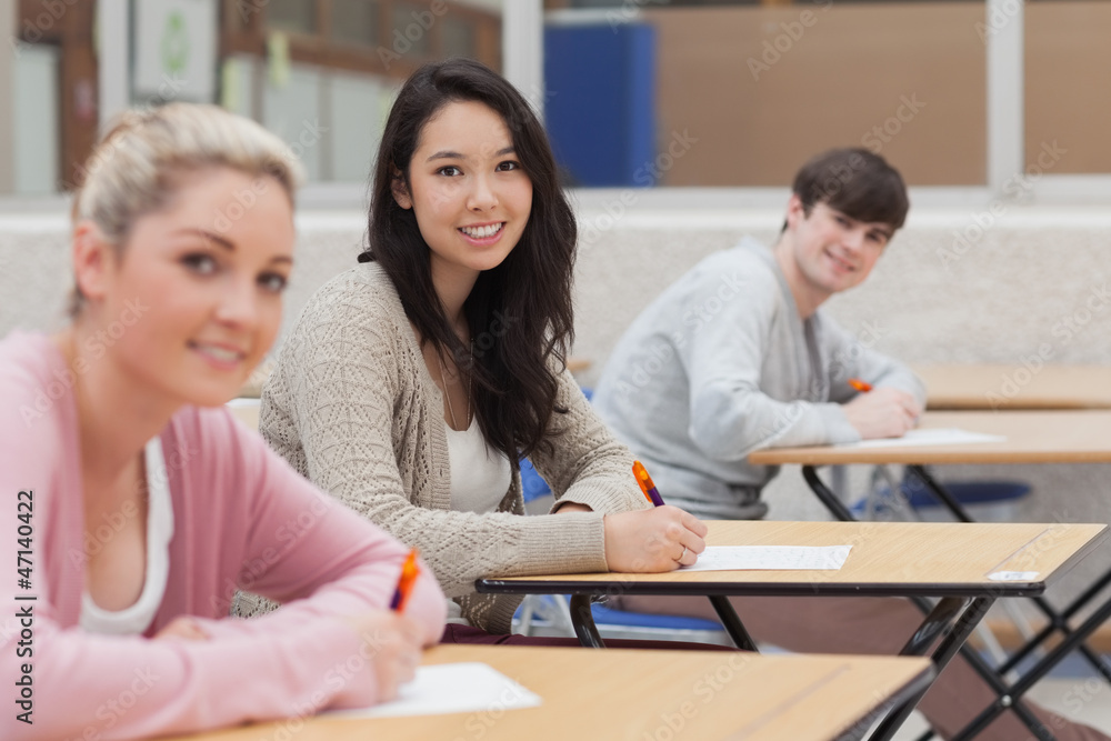 Happy students looking up from doing exam Happy students looking up from doing exam