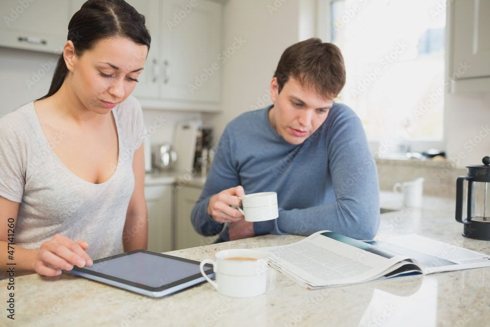 Two people reading from tablet pc and newspaper Two people reading from tablet pc and newspaper