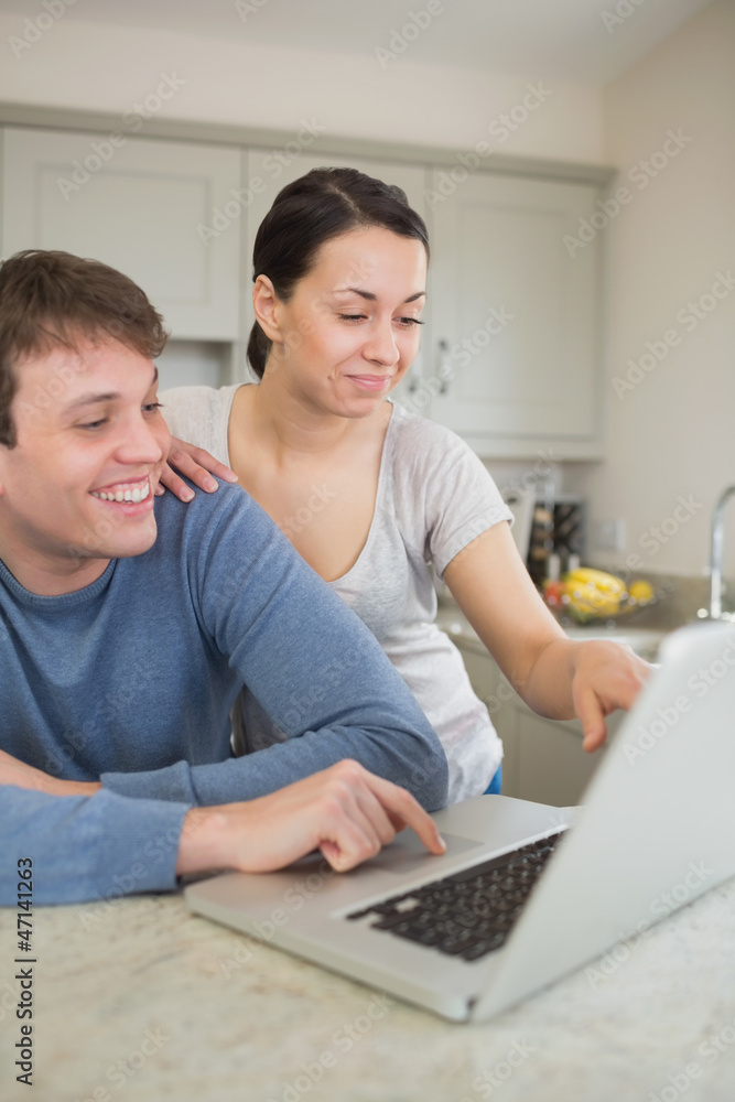 Smiling young couple using laptop