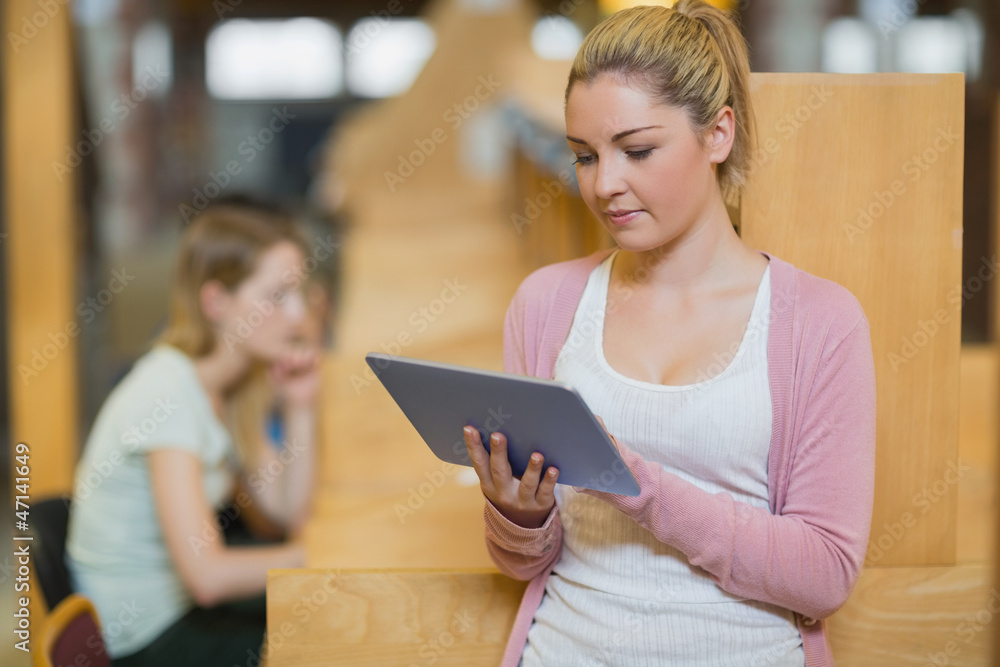Woman using tablet standing in college library Woman using tablet standing in college library