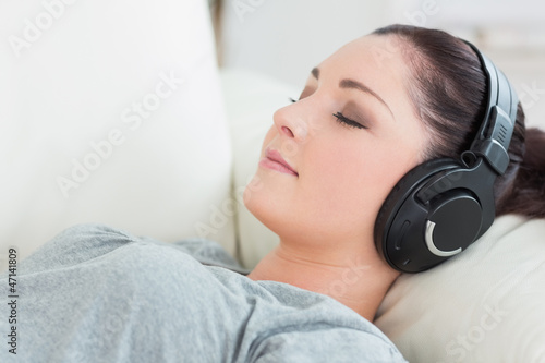 Relaxing woman lying on the couch and listening to music