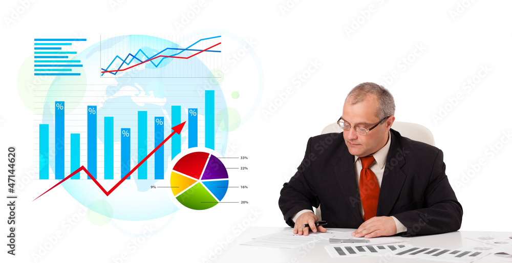 Businessman sitting at desk with statistics Businessman sitting at desk with statistics