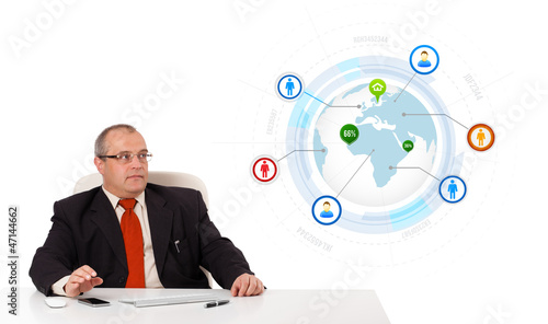 businessman sitting at desk with a globe and social icons photo