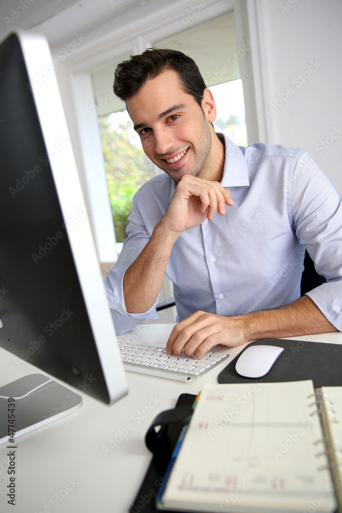 Portrait of young office worker sitting at desk