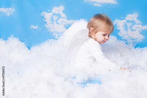 Baby with angel wings sitting in the clouds