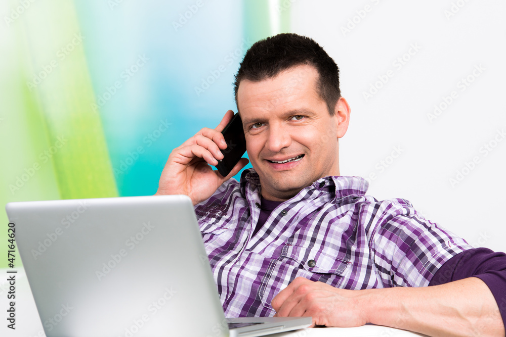 mann sitzt am notebook und telefoniert mann sitzt am notebook und telefoniert