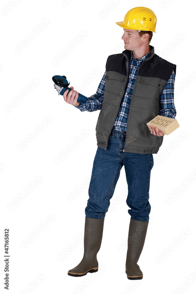 Tradesman holding an angle grinder and a brick Tradesman holding an angle grinder and a brick
