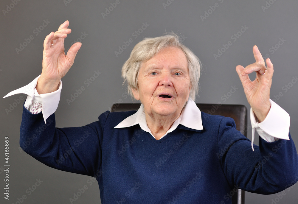 Senior happy woman with grey hairs against grey background.