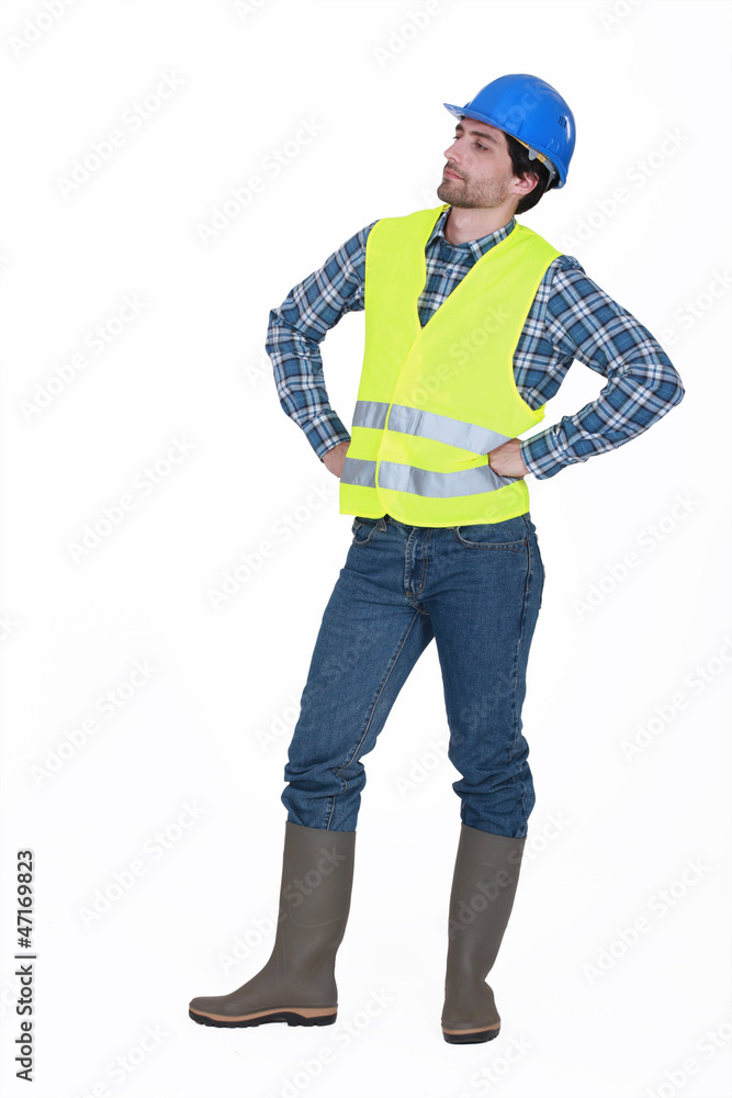 craftsman wearing hard hat standing with arms akimbo craftsman wearing hard hat standing with arms akimbo