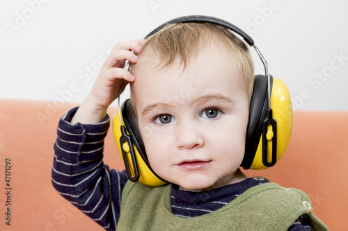 young child on couch with earmuffs
