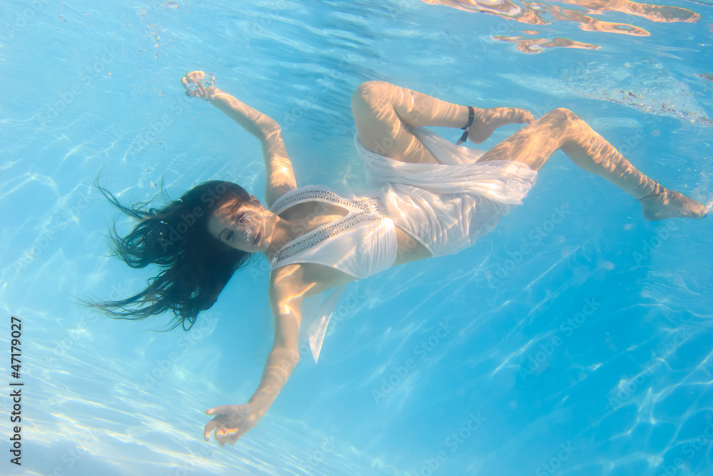 Woman in a white dress underwater in swimming pool