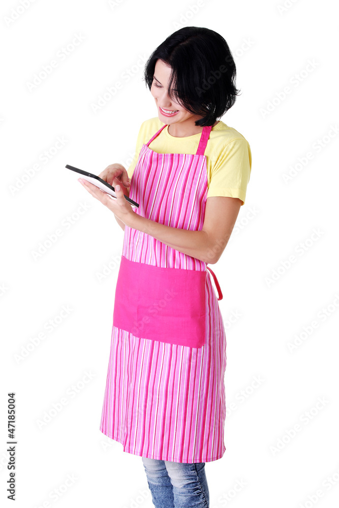 Young woman in pink apron using tablet computer Young woman in pink apron using tablet computer