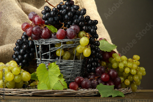 assortment of ripe sweet grapes in basket  on grey background
