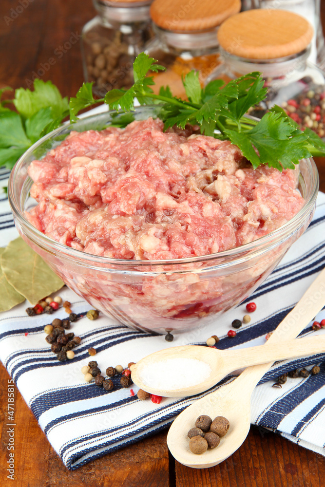 Bowl of raw ground meat with spices on wooden table Bowl of raw ground meat with spices on wooden table