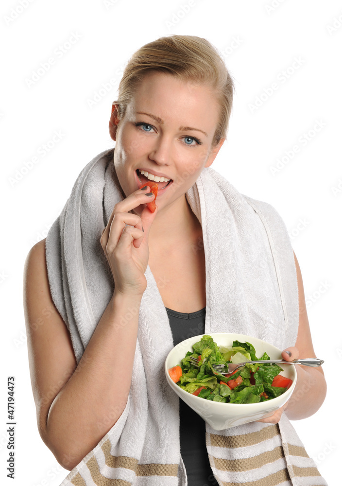 Young Woman holding a bowl of salad and eating a piece of tomato Young Woman holding a bowl of salad and eating a piece of tomato