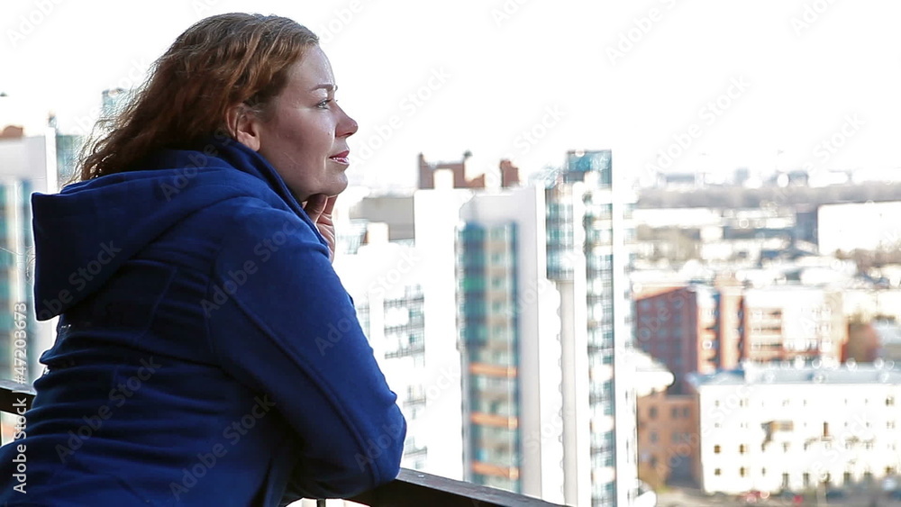 Serene young woman looking at city from altitude Serene young woman looking at city from altitude