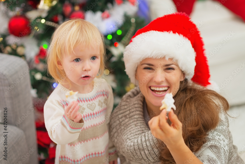 Smiling mother and baby eating Christmas cookies Smiling mother and baby eating Christmas cookies