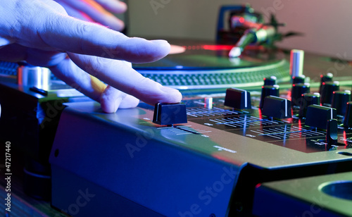 DJs hand tweaks the cross fader of a music mixer photo