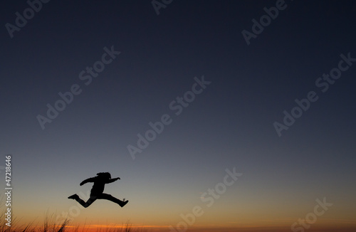 silhouetted of man jumping in sunset