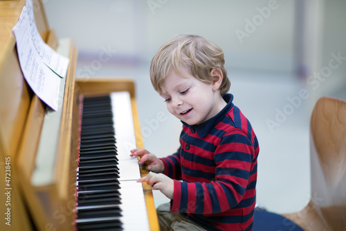 Two years old toddler boy playing piano photo