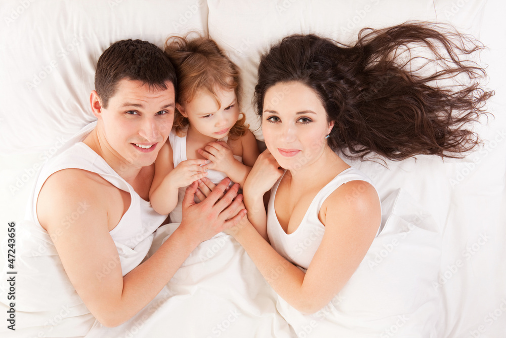 Happy family, mother, father and daughter resting on the white b Happy family, mother, father and daughter resting on the white b