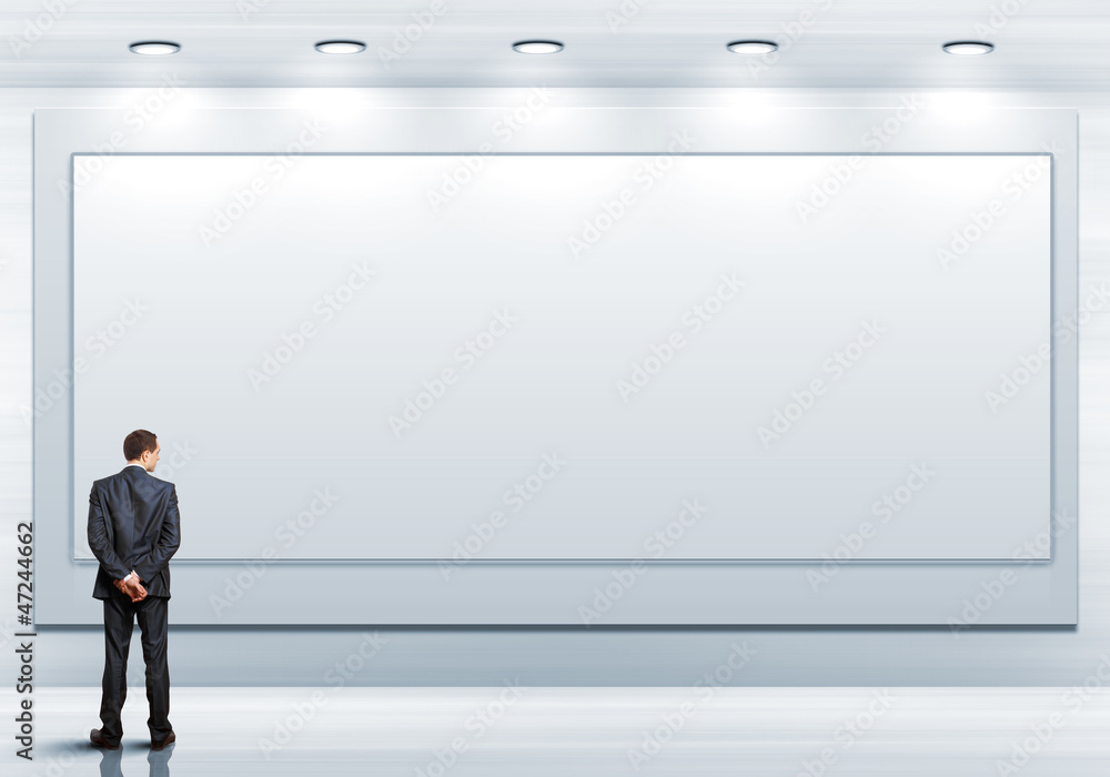 Business person standing near a blank billboard Business person standing near a blank billboard