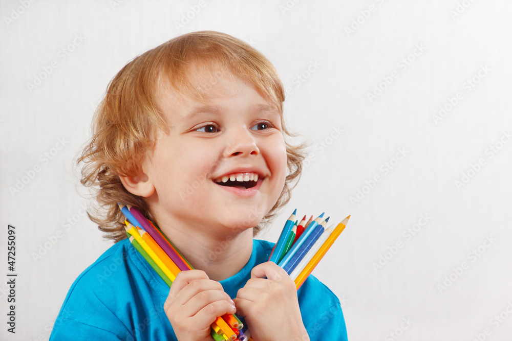 Little blond boy holds color pencils on a white background Little blond boy holds color pencils on a white background