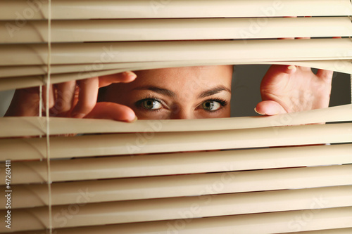 Portrait of a woman looking through out the blinds photo