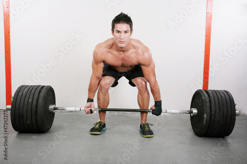 Young and muscular guy holding a barbell. Crossfit dead lift ex
