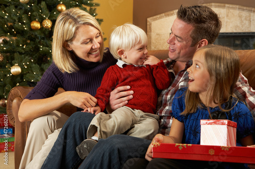 Family Opening Presents In Front Of Christmas Tree