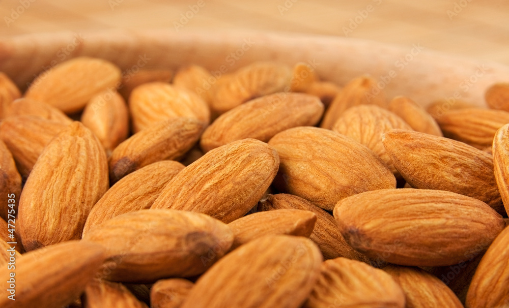 Fototapeta premium Raw almonds in wooden bowl close-up