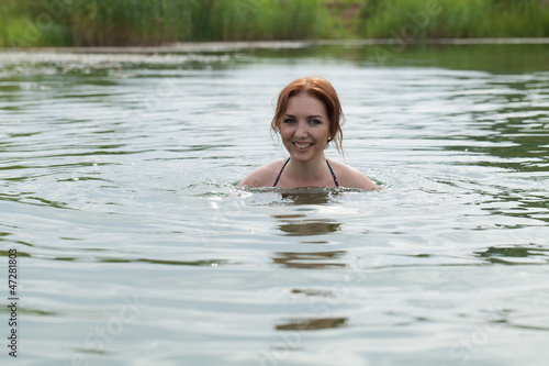Рыжеволосая девушка купается в озере