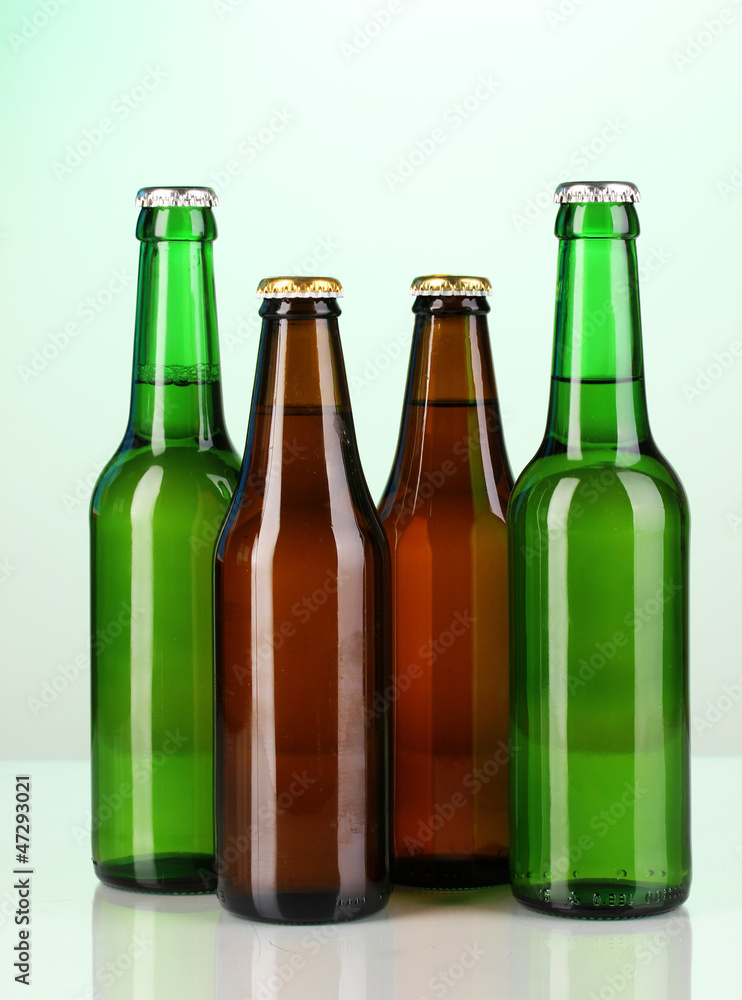 Coloured glass beer bottles on green background Coloured glass beer bottles on green background
