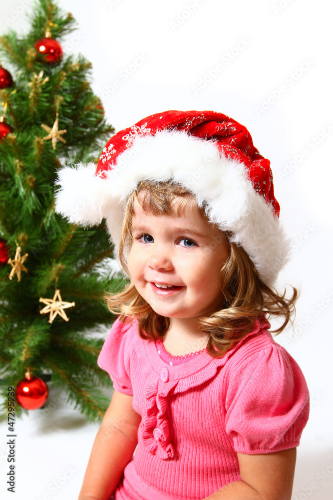 Sweet child near Christmas or New Year tree isolated on white ba