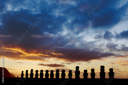 Fifteen standign moai against dramatic evening sky