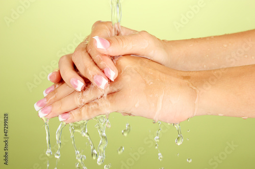 Washing woman's hands on green background close-up