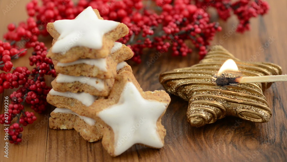 Weihnachtsgebäck wie Zimtsterne und brennende Kerze Weihnachtsgebäck wie Zimtsterne und brennende Kerze
