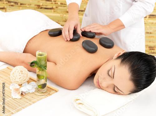 Woman having hot stone massage of back in spa salon