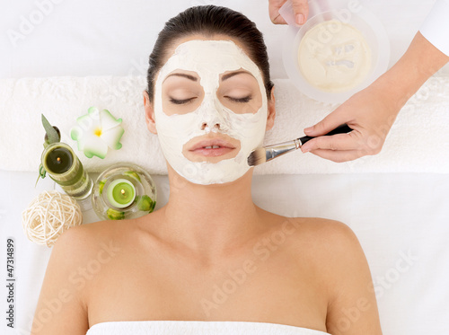 Young woman at spa salon with cosmetic mask on face