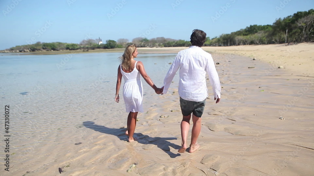 couple holding by hands and walking along coastline couple holding by hands and walking along coastline