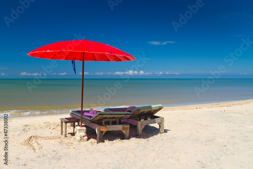 Red parasol with deckchair on tropical beach in Thailand