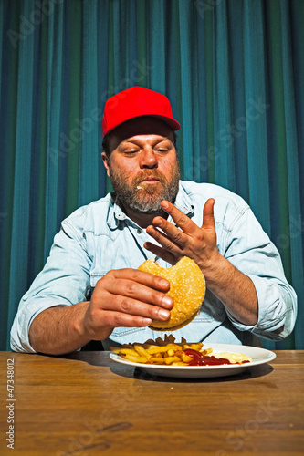 Man with beard and red cap eating fast food meal. Trucker.